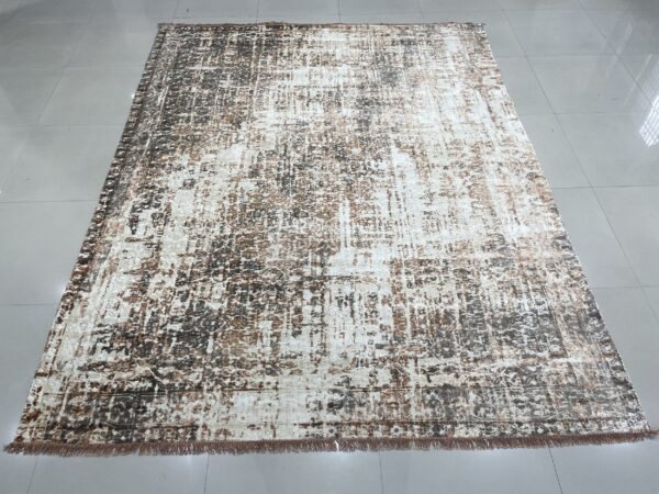 Abstract brown and cream rug with fringe displayed on a shiny gray tiled floor indoors.