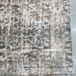 Distressed low-pile rug in cream, gray, and brown with short tassels rests on white tiled flooring.