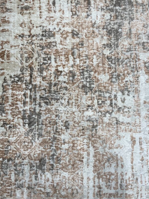 Abstract low pile rug texture blending cream, brown, and charcoal gray colors in a distressed design.