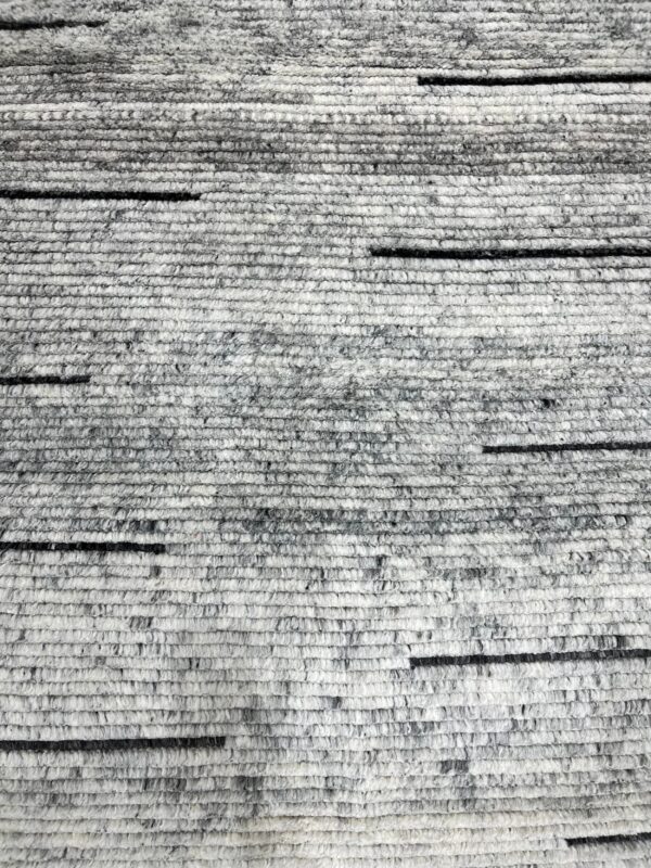 Chunky gray texture rug with heathered horizontal bands and scattered short black accents.
