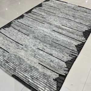 High-pile gray and white rug featuring thick horizontal lines and dark black abstract borders on tile.
