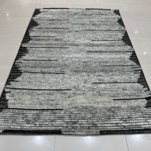 High-pile gray and white striped rug with contrasting black edges rests on shiny white floor tiles.