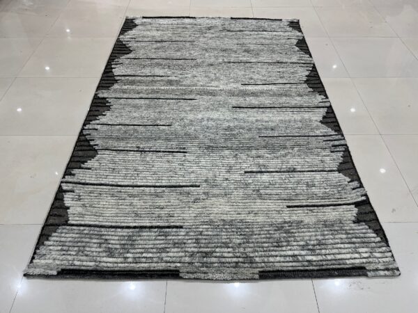 High-pile gray and white striped rug with contrasting black edges rests on shiny white floor tiles.