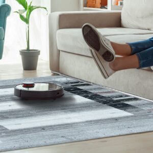 Gray geometric striped rug on wood flooring with a robot vacuum, sofa, and teal armchair.