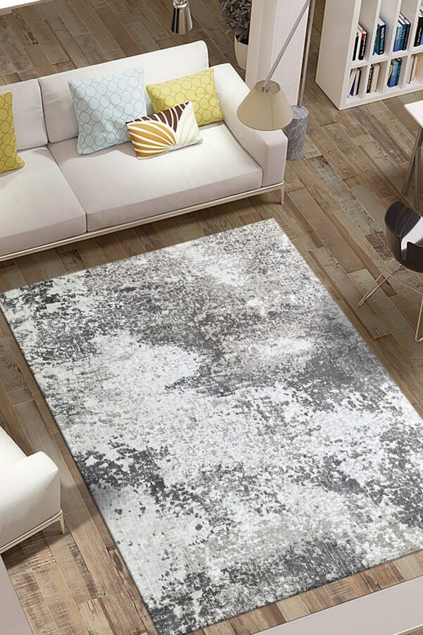Gray and white abstract area rug on wood floors, placed in front of a modern white sofa.