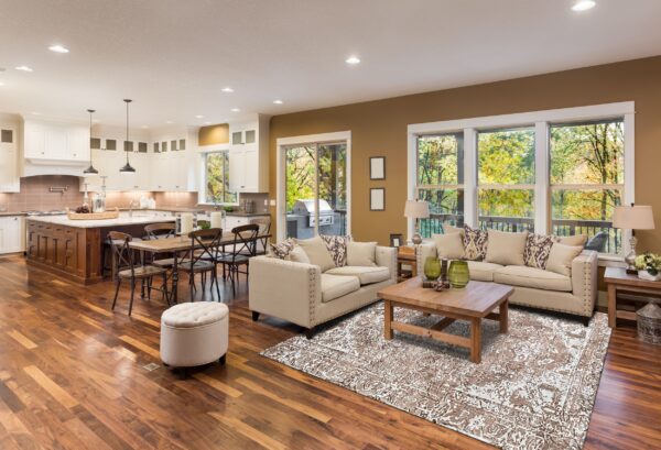 Brown and white distressed rug defining a seating area with beige couches on glossy hardwood flooring.