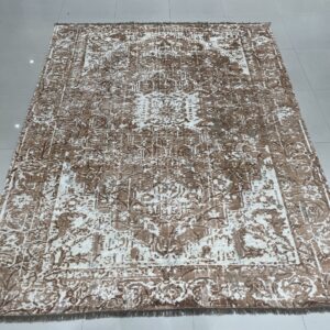 Low-pile rug with a faded brown and cream ornate pattern displayed on a reflective tiled floor.