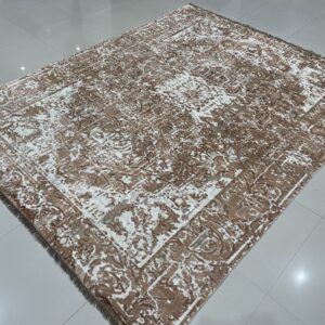 Brown and white distressed rug with a subtle sheen displays abstract patterns on glossy white tile flooring.