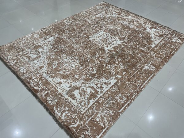 Brown and white distressed rug with a subtle sheen displays abstract patterns on glossy white tile flooring.