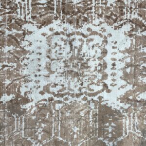 Detail shot of a brown and white rug showing a distressed, abstract pattern and varying pile texture.