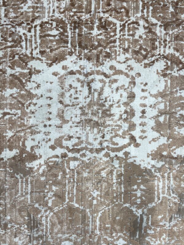 Detail shot of a brown and white rug showing a distressed, abstract pattern and varying pile texture.