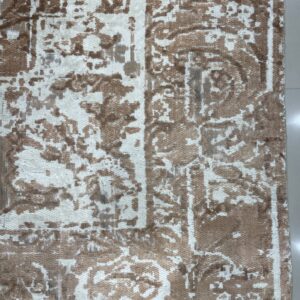 Low-pile rug featuring a distressed brown and cream abstract pattern on a light tiled floor with fringe.