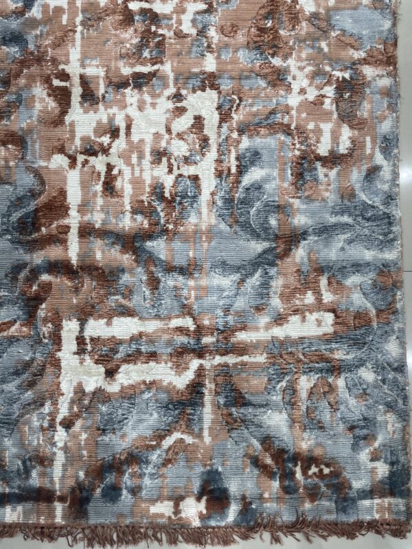 Dimensional abstract rug with stripes and shapes in blue, brown, and white, lying on tile flooring.