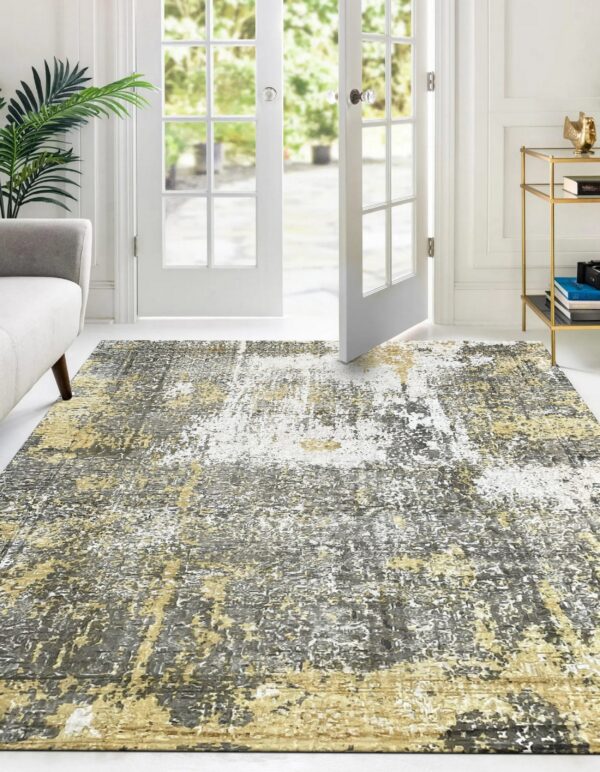 Abstract gray, gold, and white rug placed on a white floor near french doors and a couch.