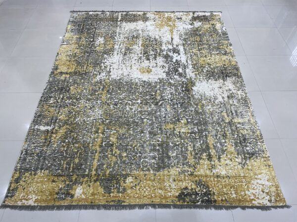 Low-pile rug with a distressed pattern of gold, white, and charcoal gray on tile.