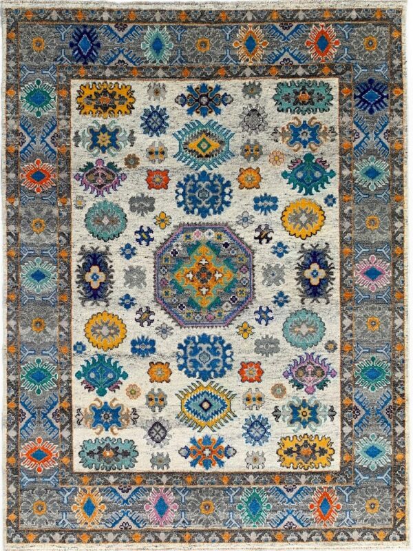 White tribal rug with scattered multi-colored medallions and a wide gray geometric border.