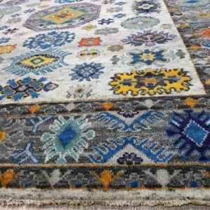 Low-pile rug in white, gray, blue, and yellow with abstract medallions on light wood flooring.