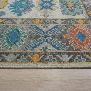 Light gray and dark gray rug with bright blue, orange, and yellow geometric motifs on light wood floor.