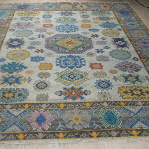 Colorful rug with bright floral medallions on a light grey field and a dark grey geometric border.