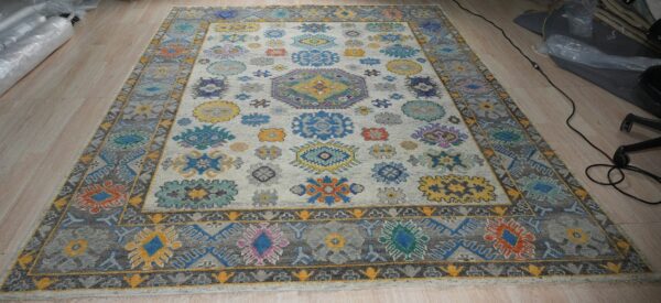 Colorful rug with bright floral medallions on a light grey field and a dark grey geometric border.