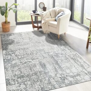Gray abstract rug defines a sunny living space with light flooring and a white armchair near large windows.