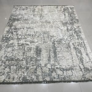 Distressed rectangular rug in cream, gray, and taupe tones on a shiny tiled floor.