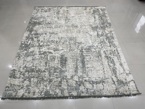 Distressed rectangular rug in cream, gray, and taupe tones on a shiny tiled floor.