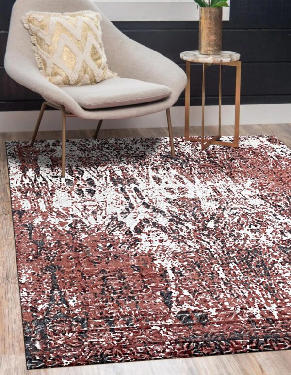 Rust, white, and black distressed rug on wood flooring beneath a gray chair and marble side table.