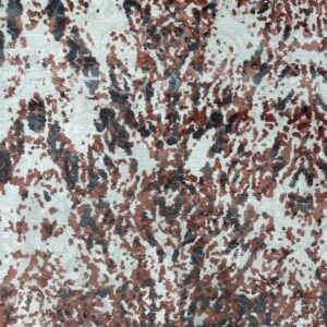 Detailed view of a textured rug with mottled charcoal and terracotta shapes on a cream background.