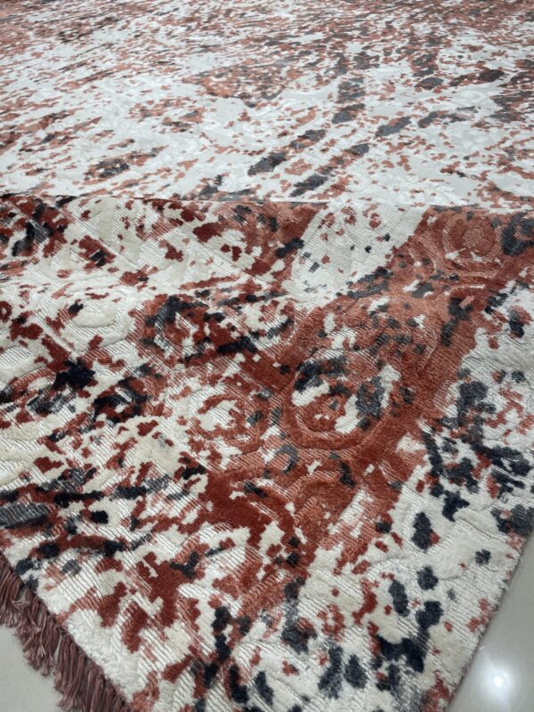 Textured rug detail showing mottled red, cream, and charcoal patterns with varying pile height and visible fringe.