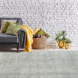 Textured gray and white striped rug with a gray sofa, woven basket, and gold planters nearby.