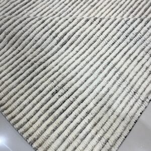 High-pile rug with alternating cream and gray thick ribbed stripes on a shiny white tile floor.