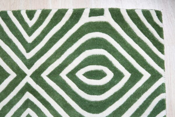 Textured green and white rug featuring thick, geometric stripes forming nested diamond shapes on wood flooring.