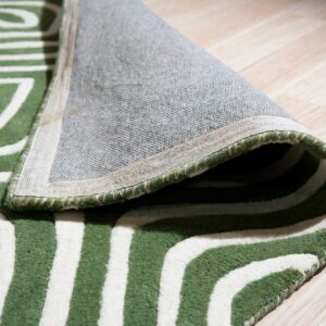 Geometric green and white rug is rolled back revealing its woven backing on light plank flooring.