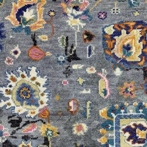 Close-up of a textured gray rug with scattered colorful stylized traditional patterns.