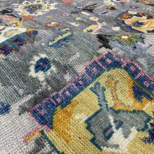Detailed view of a grey high-pile rug with scattered blue, yellow, orange, and pink colorful patterns.