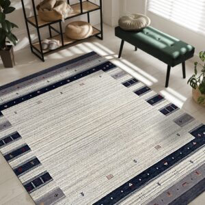 Striped gray and navy geometric rug on light wood flooring next to a green velvet bench.