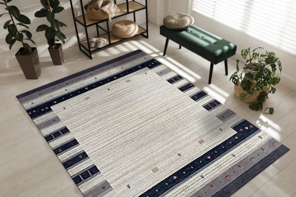 Striped gray and navy geometric rug on light wood flooring next to a green velvet bench.