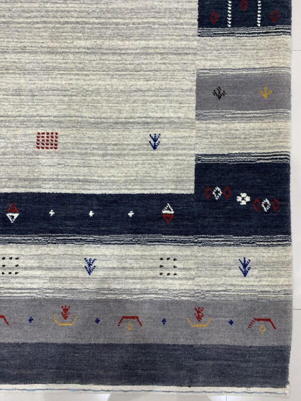 Gray, navy, and white striped area rug with textured pile and scattered red and yellow geometric patterns.