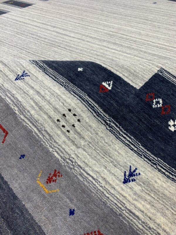 Textured rug with wide diagonal stripes in heathered gray and navy blue featuring small multicolored patterns.