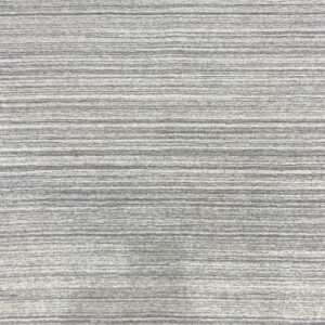 A gray striated rug surface with horizontal bands and small red and dark blue geometric patterns.