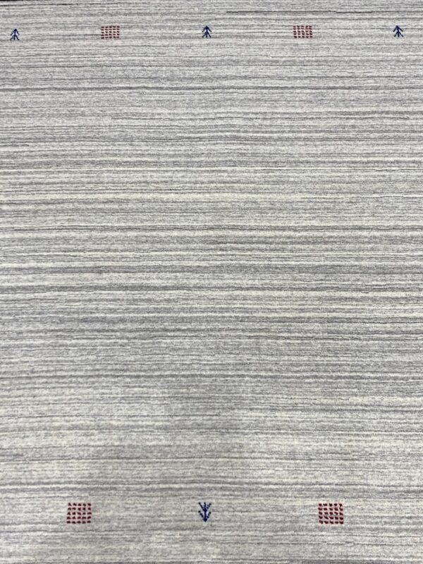 A gray striated rug surface with horizontal bands and small red and dark blue geometric patterns.