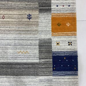 Close-up of a high-pile rug with gray striping and bold vertical blocks in yellow, orange, and navy blue.