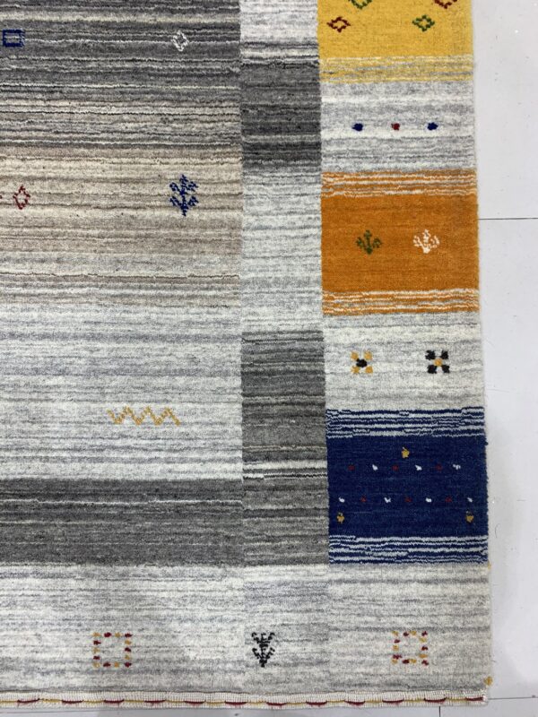 Close-up of a high-pile rug with gray striping and bold vertical blocks in yellow, orange, and navy blue.