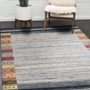 Striped blue and cream rug with multicolored borders on dark wood, next to a white furry chair.