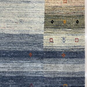 Detail of a textured rug showing blue, gray, and cream horizontal stripes with geometric accents.