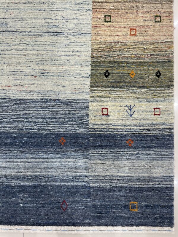 Detail of a textured rug showing blue, gray, and cream horizontal stripes with geometric accents.