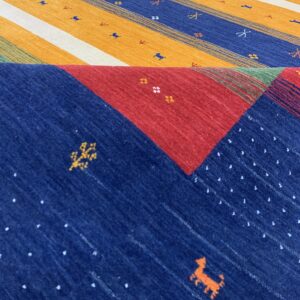 Colorful folded rug displays multi-colored stripes and contrasting red and blue geometric patterns.