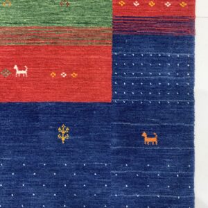 Textured rug detail with bold blocks of green, red, and blue, featuring small animal and plant motifs.