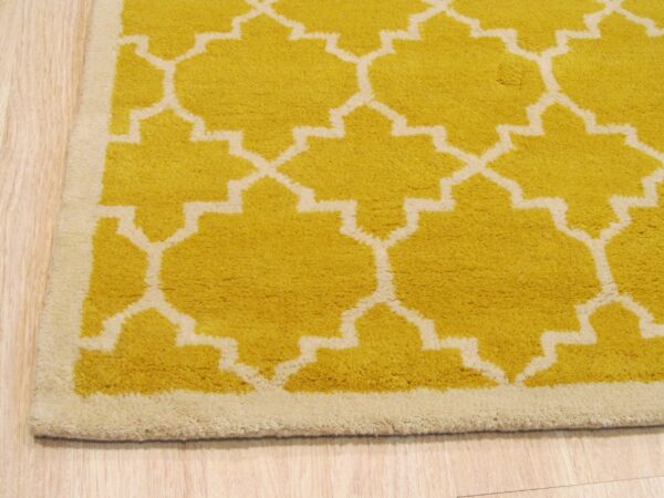 A yellow and cream high-pile rug with a geometric pattern sits on light wood planks.